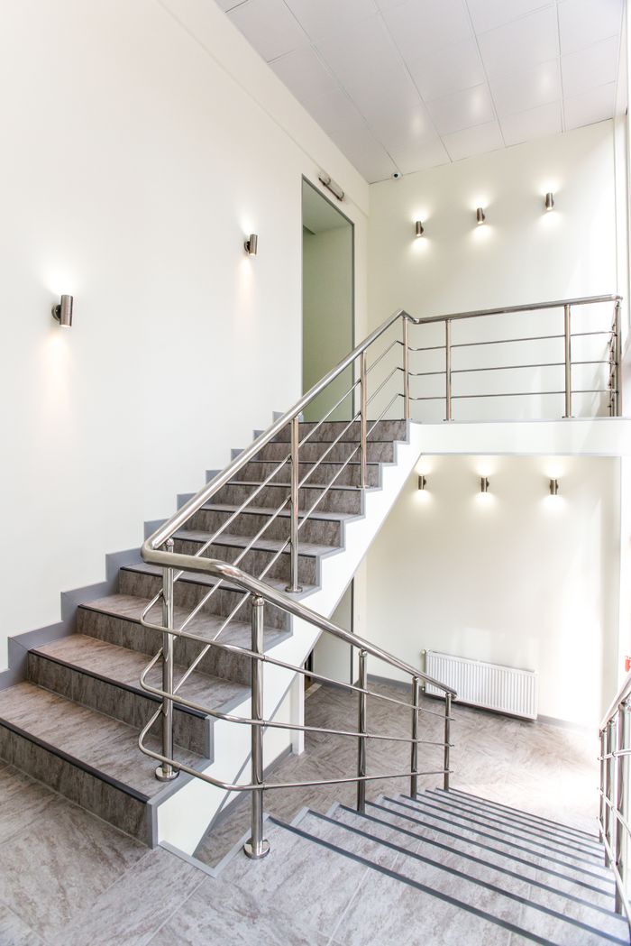 About Bright indoor staircase with stainless steel railings and modern wall lights