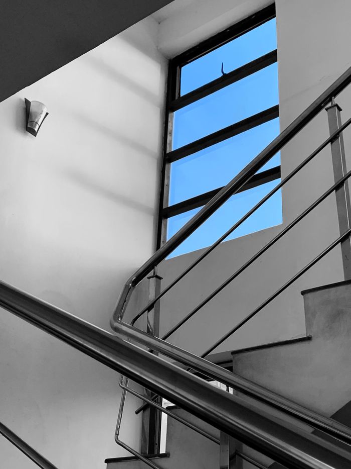 Services Stainless steel railing staircase with a clear sky view through the window.